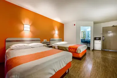 two beds in a hotel room with orange walls at Motel 6-Burlington, ON - Toronto West - Oakville in Burlington