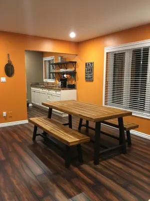 a dining room with a wooden table and benches at The Village Suites in Wellington