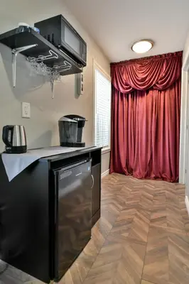 a kitchen with a stove and a red curtain at The Village Suites in Wellington