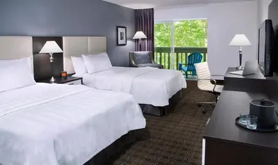a hotel room with two beds and a desk at Toronto Don Valley Hotel and Suites in Toronto