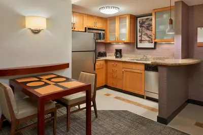 a small kitchen with a table and a refrigerator at Residence Inn by Marriott Gravenhurst Muskoka Wharf in Gravenhurst