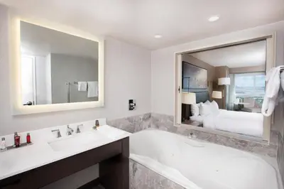 a bathroom with a tub and a sink and a bed at Niagara Falls Marriott Fallsview Hotel & Spa in Niagara Falls