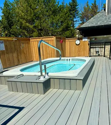 a pool with a hot tub on a wooden deck at Condo Loft at Blue Mountain in Blue Mountains