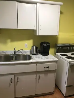 a kitchen with white cabinets and a sink and a stove at Wasaga Bridge Cottages in Wasaga Beach