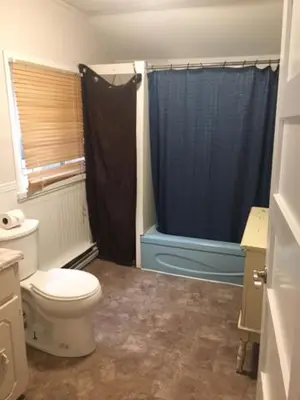 a bathroom with a toilet and a blue shower at Wasaga Bridge Cottages in Wasaga Beach