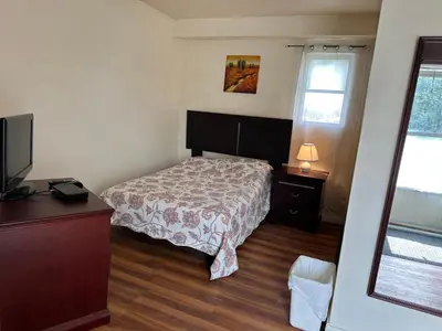 a bedroom with a bed and a dresser and a television at Carriage Inn Motel in Peterborough