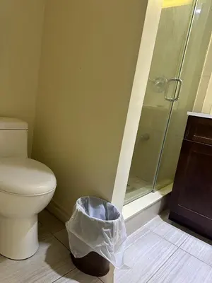 a bathroom with a toilet and a shower with a trash can at Carriage Inn Motel in Peterborough