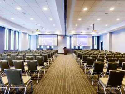a large room with rows of chairs and two screens at Residence & Conference Centre - Toronto Downtown in Toronto