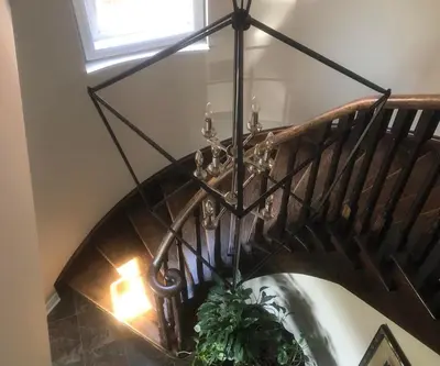 a spiral staircase with a chandelier and a plant at Willow Pond Satellite B&B in Port Perry