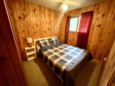 a bedroom with a bed in a wooden room at High Falls Bay Cottages, Camping & Waterpark in Bracebridge