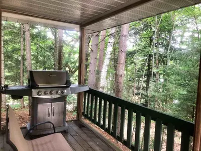 a screened in porch with a grill on a deck at High Falls Bay Cottages, Camping & Waterpark in Bracebridge