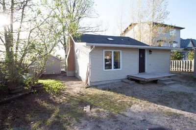 a small white house with a bench in the yard at 58 River Rd. East in Wasaga Beach