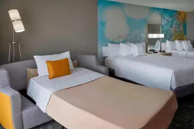 a hotel room with two beds and a couch at Courtyard by Marriott Toronto Airport in Toronto