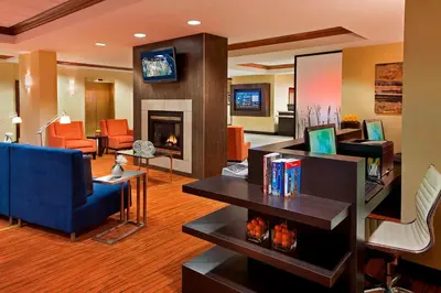 a living room with a blue couch and a fireplace at Courtyard by Marriott Toronto Airport in Toronto