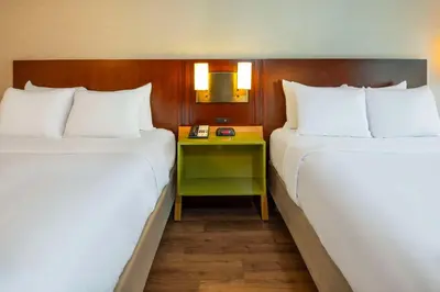 two beds in a hotel room with a table between them at Comfort Inn in Newmarket