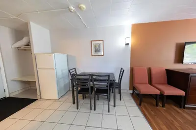 a dining room with a table and chairs and a refrigerator at Villager Lodge Niagara Falls in Niagara Falls