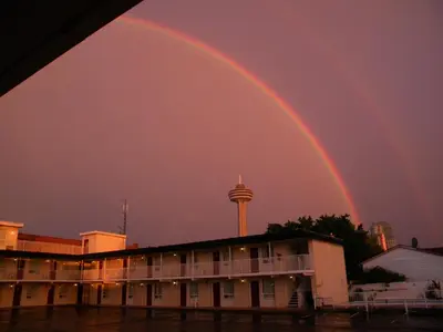 a double rainbow over a building with a tower in the background at Fairway Inn by the Falls in Niagara Falls
