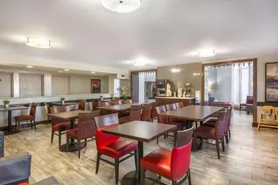 a restaurant with wooden tables and red chairs at Comfort Inn in Burlington