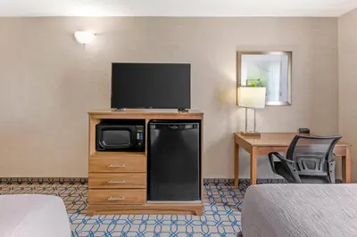 a hotel room with a flat screen tv on a dresser at Quality Suites in Whitby