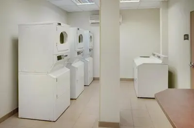a row of white washers and dryers in a room at Staybridge Suites Oakville Burlington by IHG in Oakville