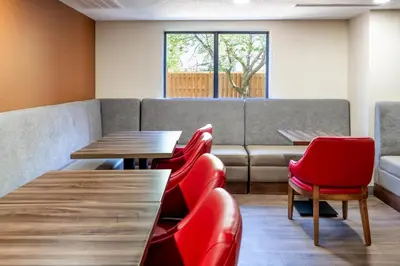 a waiting room with red chairs and tables and a couch at Comfort Suites in London