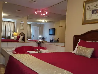 a bedroom with a large red bed and a mirror at Niagara Inn & Suites in Niagara Falls