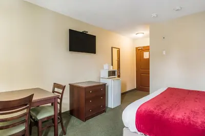 a hotel room with a bed and a desk and a table at Knights Inn Orillia in Orillia