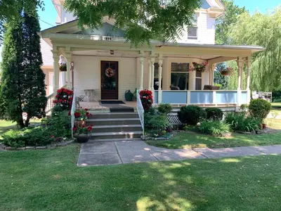 a white house with flowers on the front porch at Green Oaks B&B in Niagara on the Lake