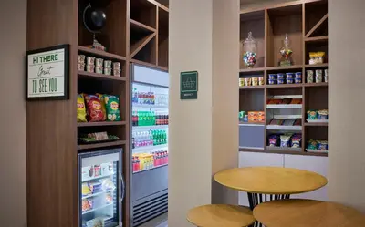 a kitchen with a refrigerator and two tables in a store at Holiday Inn & Suites Oakville at Bronte by IHG in Oakville