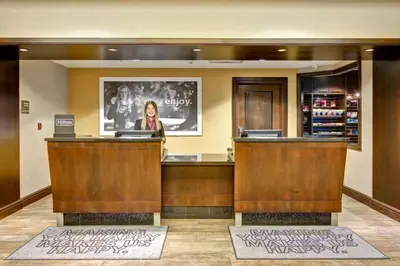 a woman standing at a counter in a lobby at Hampton Inn by Hilton Toronto Airport Corporate Centre in Toronto