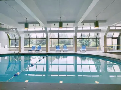 a swimming pool with blue chairs in a building at Briars Resort and Spa in Georgina