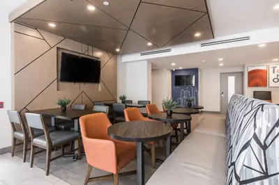 a waiting room with tables and chairs and a flat screen tv at Holiday Inn Express Toronto-North York by IHG in Toronto