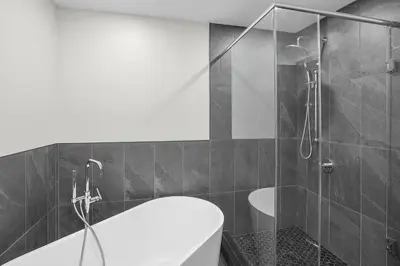 a bathroom with a shower and a toilet and a tub at The Jordan Hotel Ramada by Wyndham in Jordan