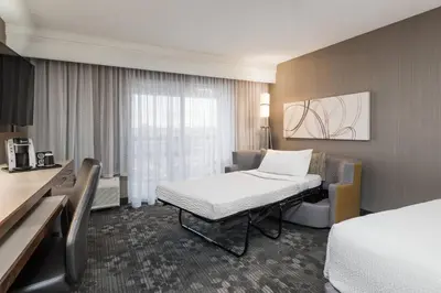 a hotel room with a bed and a chair and a desk at Courtyard by Marriott Toronto Vaughan in Vaughan