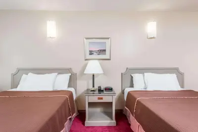 a hotel room with two beds and a table with a lamp at London Travel Inn in London