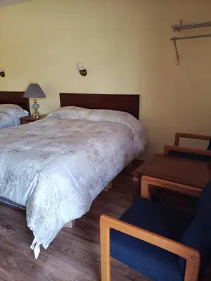 a bedroom with two beds and a chair at Olympia Motel in Niagara Falls