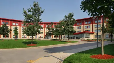 a large red building with trees in front of it at Residence & Conference Centre - Oakville in Oakville