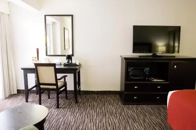 a hotel room with a desk with a tv and a table at Admiral Inn Hamilton in Hamilton