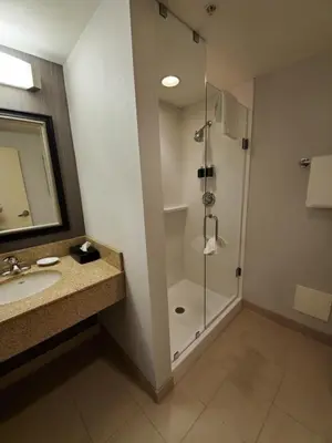 a bathroom with a shower and a sink and a mirror at Courtyard by Marriott Hamilton in Hamilton