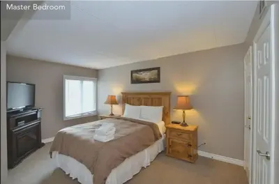 a bedroom with a bed with two lamps and a television at Large modern ground floor condo at Mountain Walk in Blue Mountains