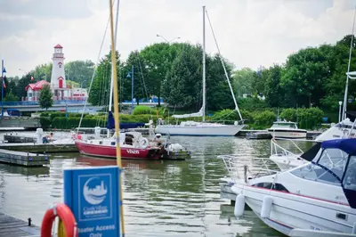 a group of boats docked in a marina with a lighthouse at The Waterside Inn in Mississauga