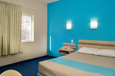 a blue room with a bed and a window at Motel 6-Peterborough, ON in Peterborough
