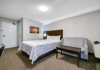 a hotel room with a bed and a chair at Deluxe Inn in Toronto