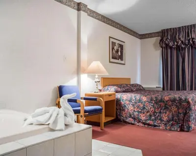 a hotel room with a bedroom with a bed and a chair at Econo Lodge By the Falls in Niagara Falls