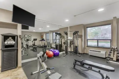 a gym with cardio equipment and a flat screen tv at Best Western Plus Rose City Suites in Welland
