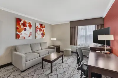 a living room with a couch and a desk at Best Western Plus Rose City Suites in Welland