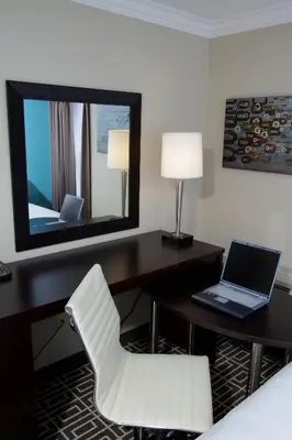 a hotel room with a desk with a laptop and a mirror at Visitor's Inn in Hamilton