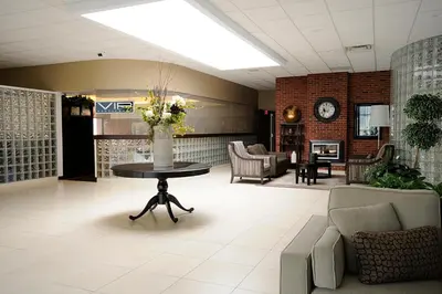 a lobby with a table and chairs and a fireplace at Visitor's Inn in Hamilton