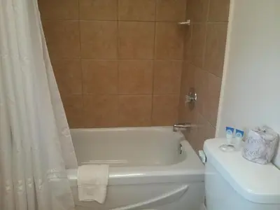 a bathroom with a white tub and a toilet at Port Motel in Port Colborne