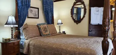 a bedroom with a bed with blue curtains and a mirror at A Night to Remember B & B in Niagara Falls